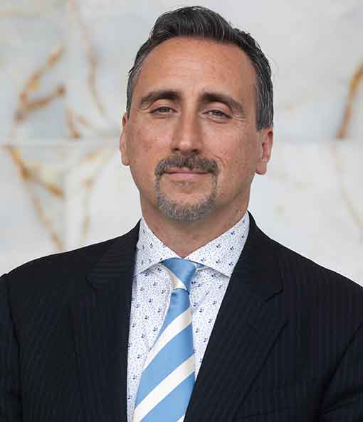 A man in a suit and tie standing next to a wall.