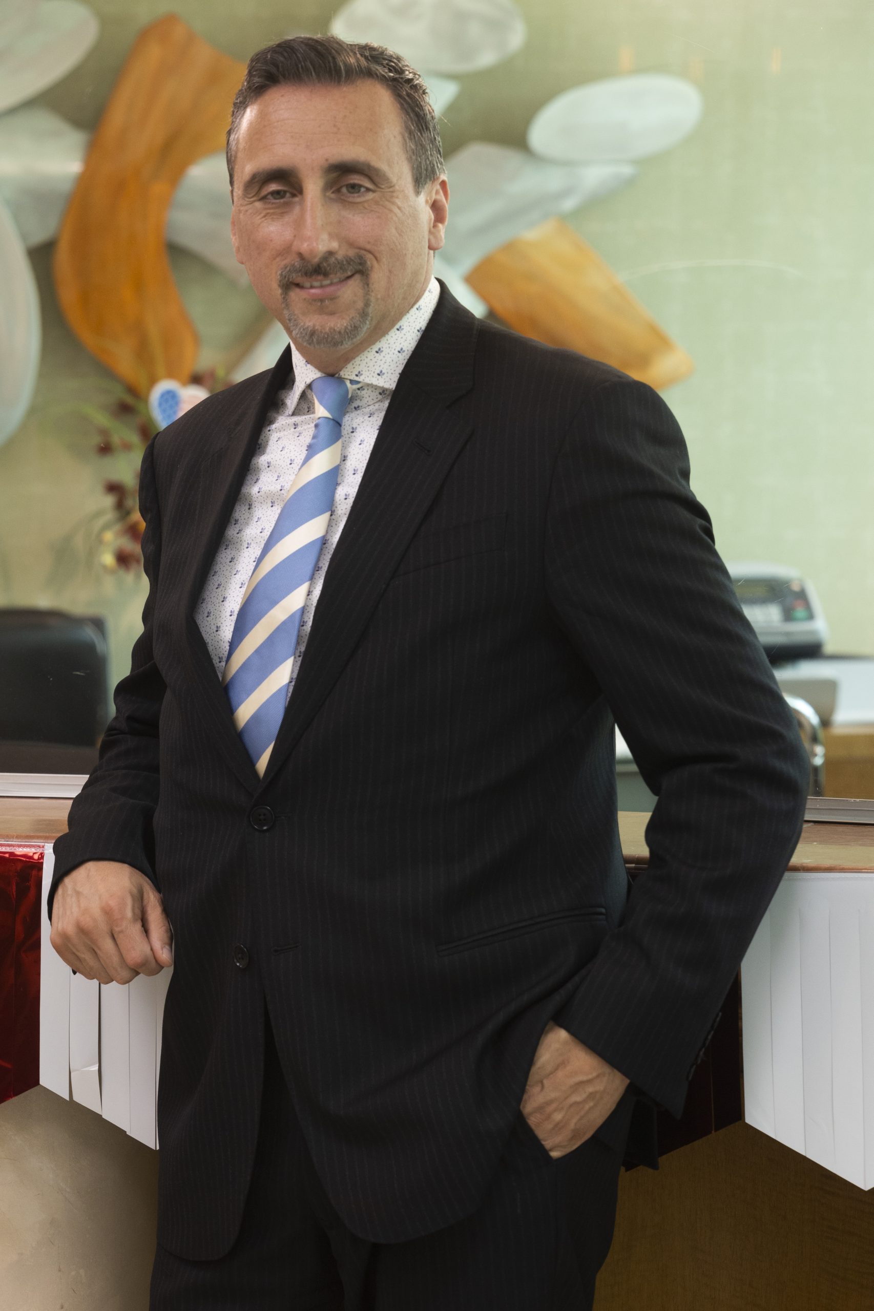 A man in suit and tie standing next to a counter.